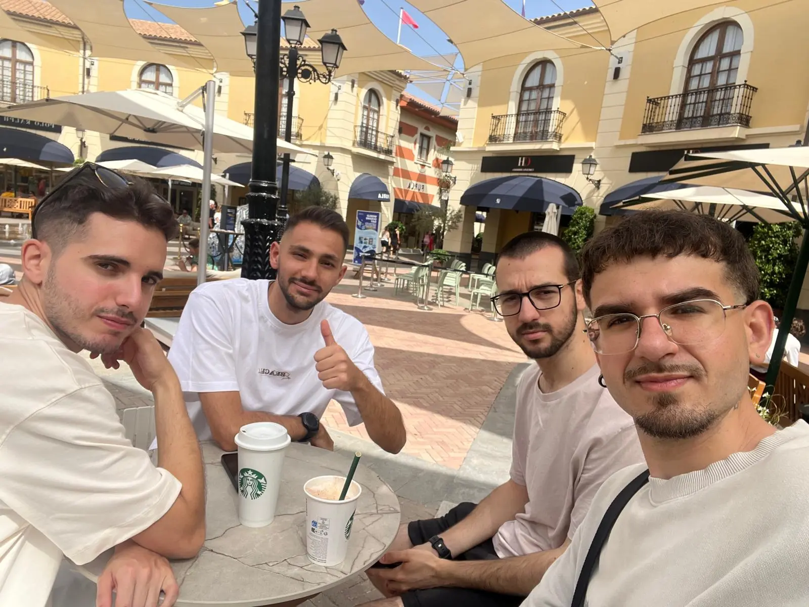 Selfie of Matías with three friends at a café terrace on a sunny day